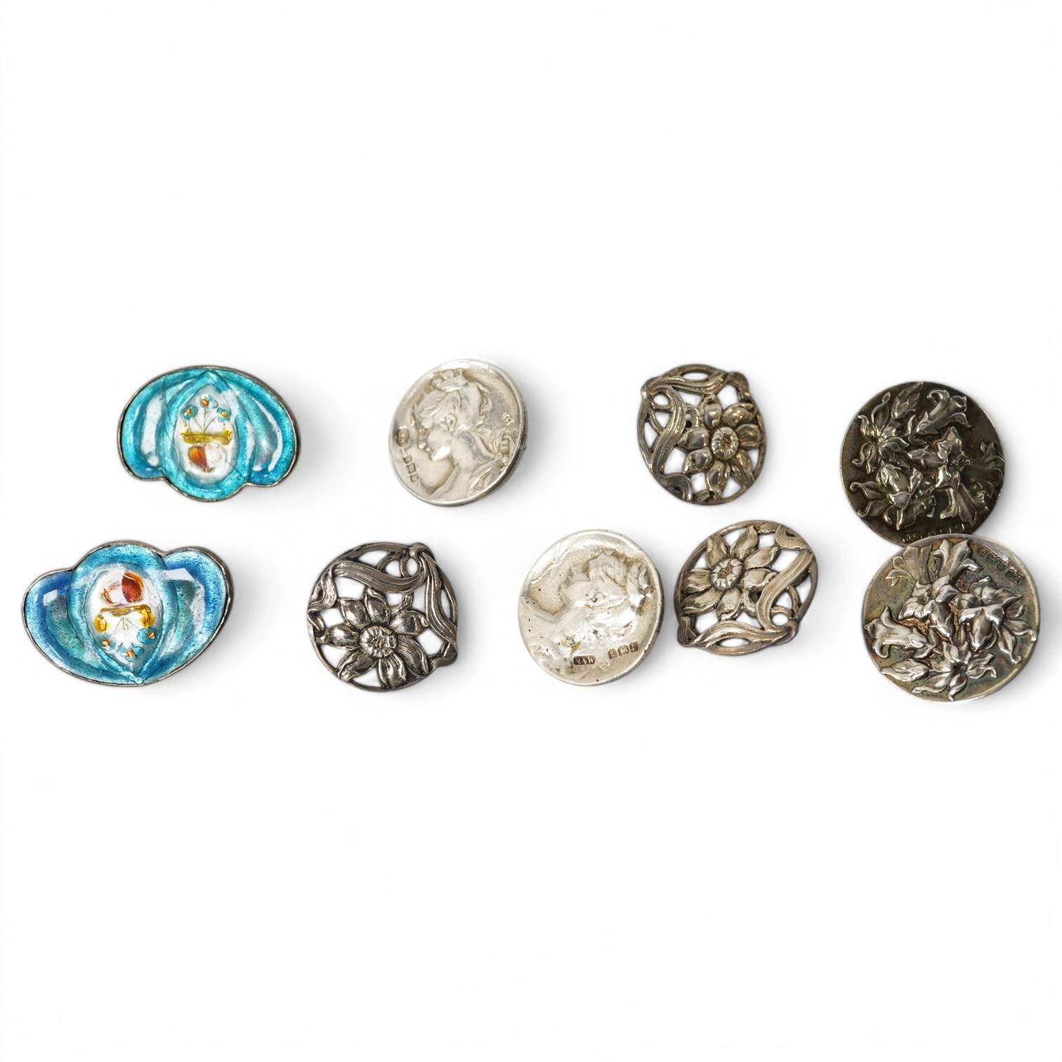 A pair of Art Nouveau enamelled white metal buttons, 33mm, a set of 3 cast silver flower buttons, H.C. Birmingham 1911, 23mm, a pair of silver lily pattern buttons, J.G. Birmingham 1903, 27mm and a pair of cast silver Ar